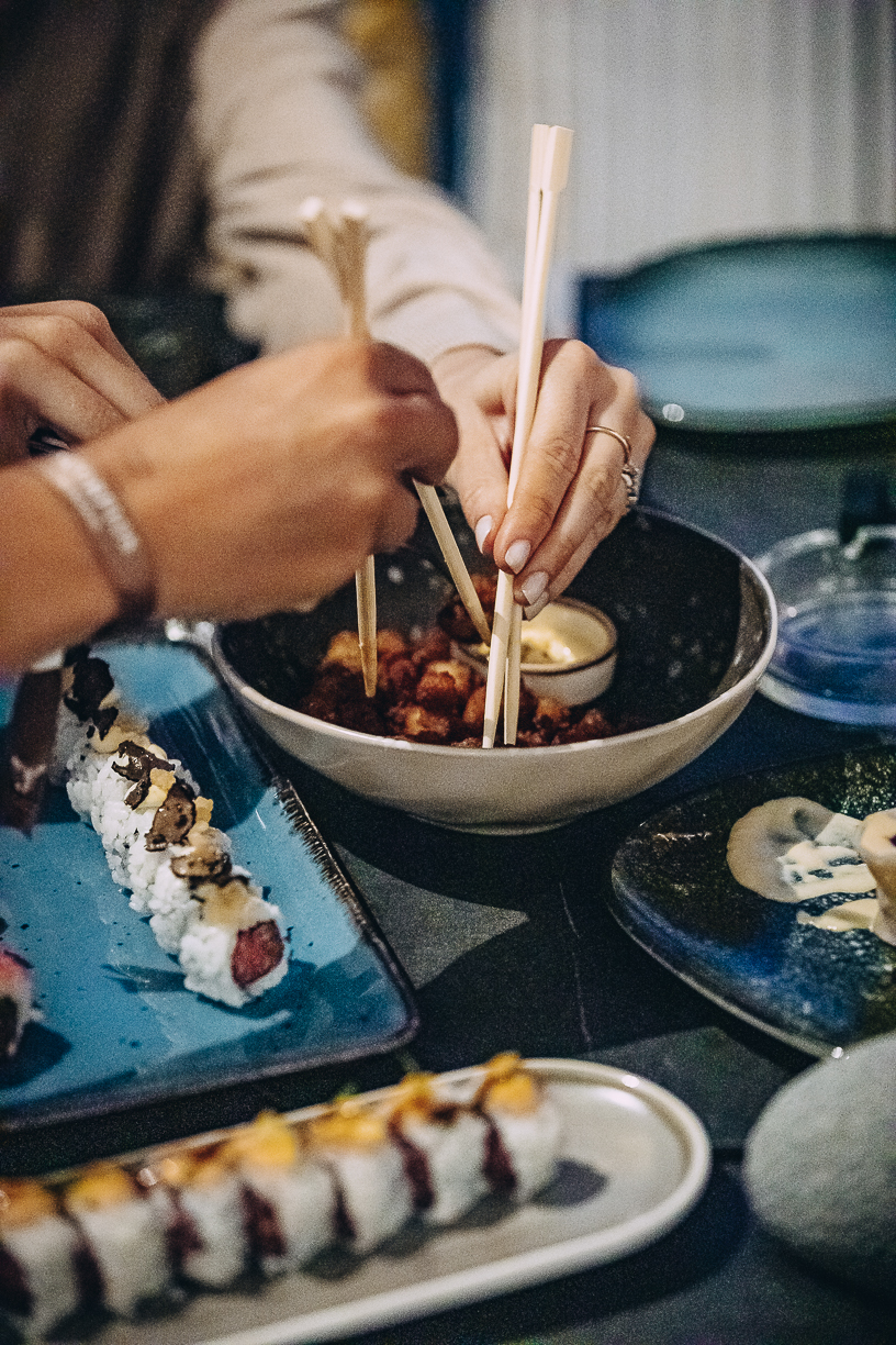 A table laid with several dishes to share, plates crossing the middle of the cloth.