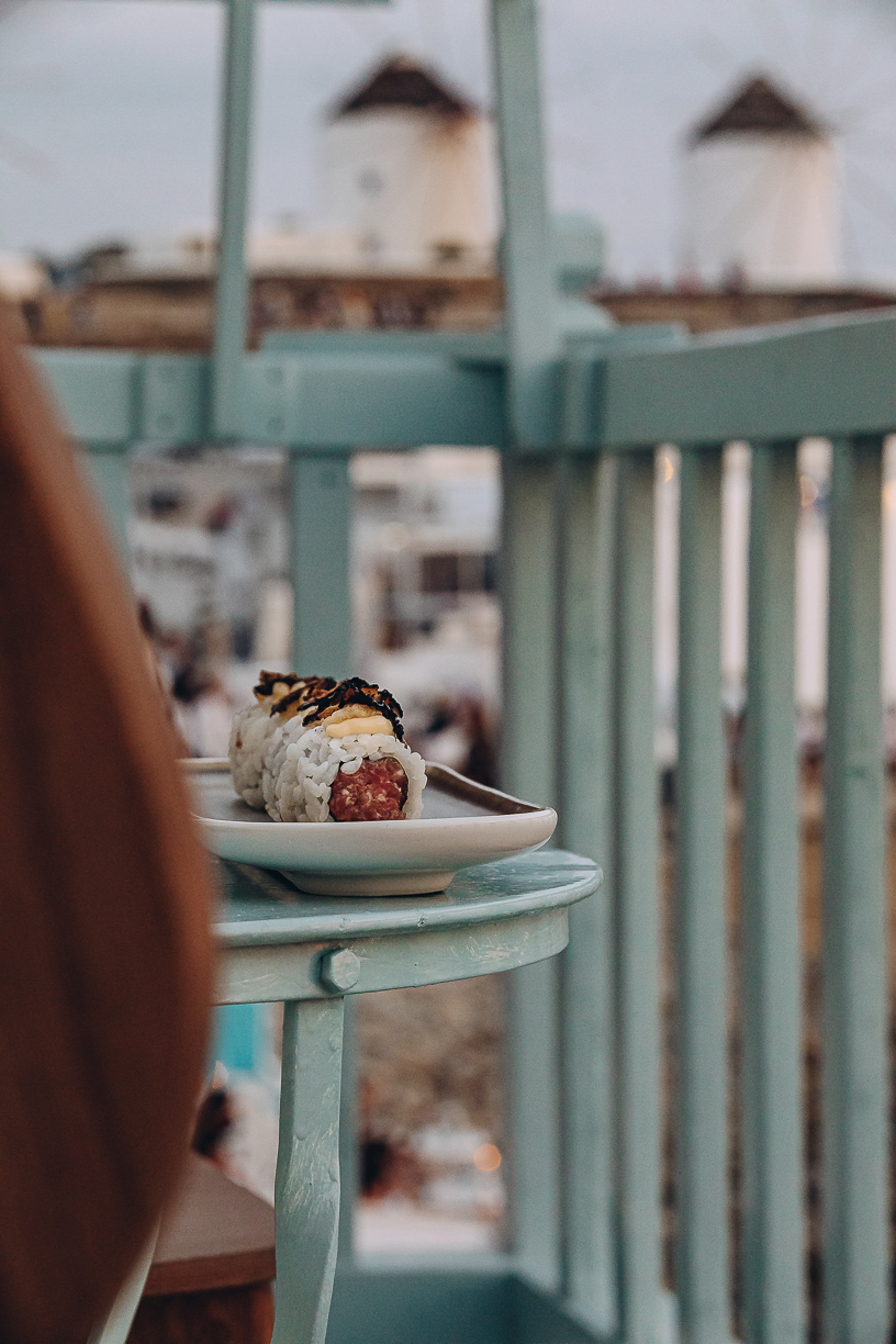 A plate of beef sushi on the terrace rail with the sea behind.