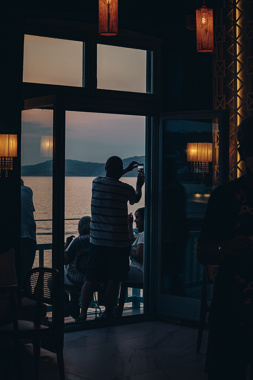 Guests at the open window inside Cantera as the light drops over the sea.