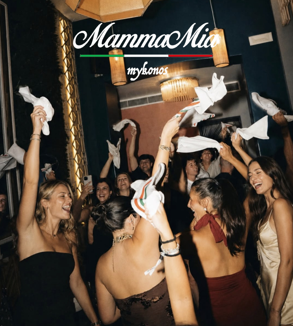 Guests on their feet at Mamma Mia Night, waving napkins above their heads under the lamps at Cantera.