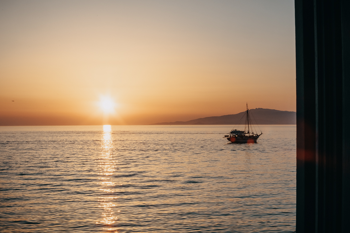 The sun on the horizon over open sea, seen from the balcony at Cantera with a boat crossing the light.