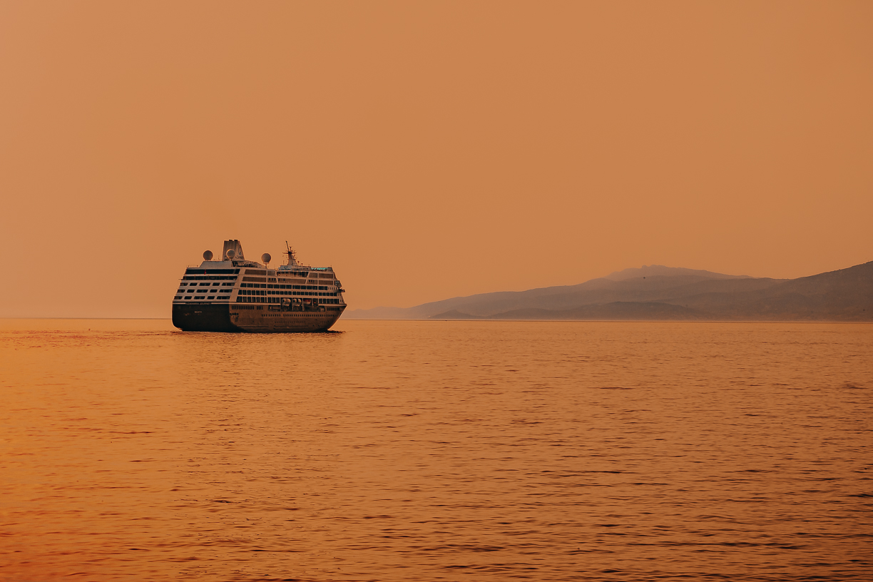 The Aegean turned copper under a low sun, a boat crossing the light.