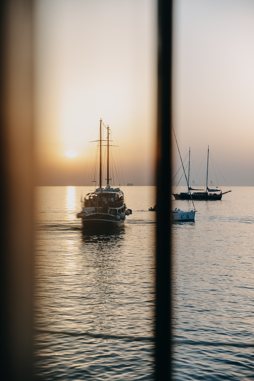 The sun on the horizon framed by an open window over the bay.
